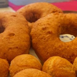 A food worker is frying donuts in a deep fryer