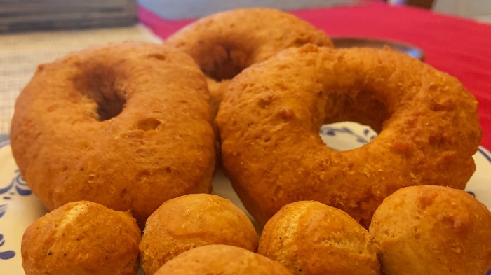 A food worker is frying donuts in a deep fryer