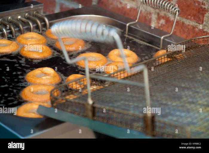 A food worker is frying donuts in a deep fryer